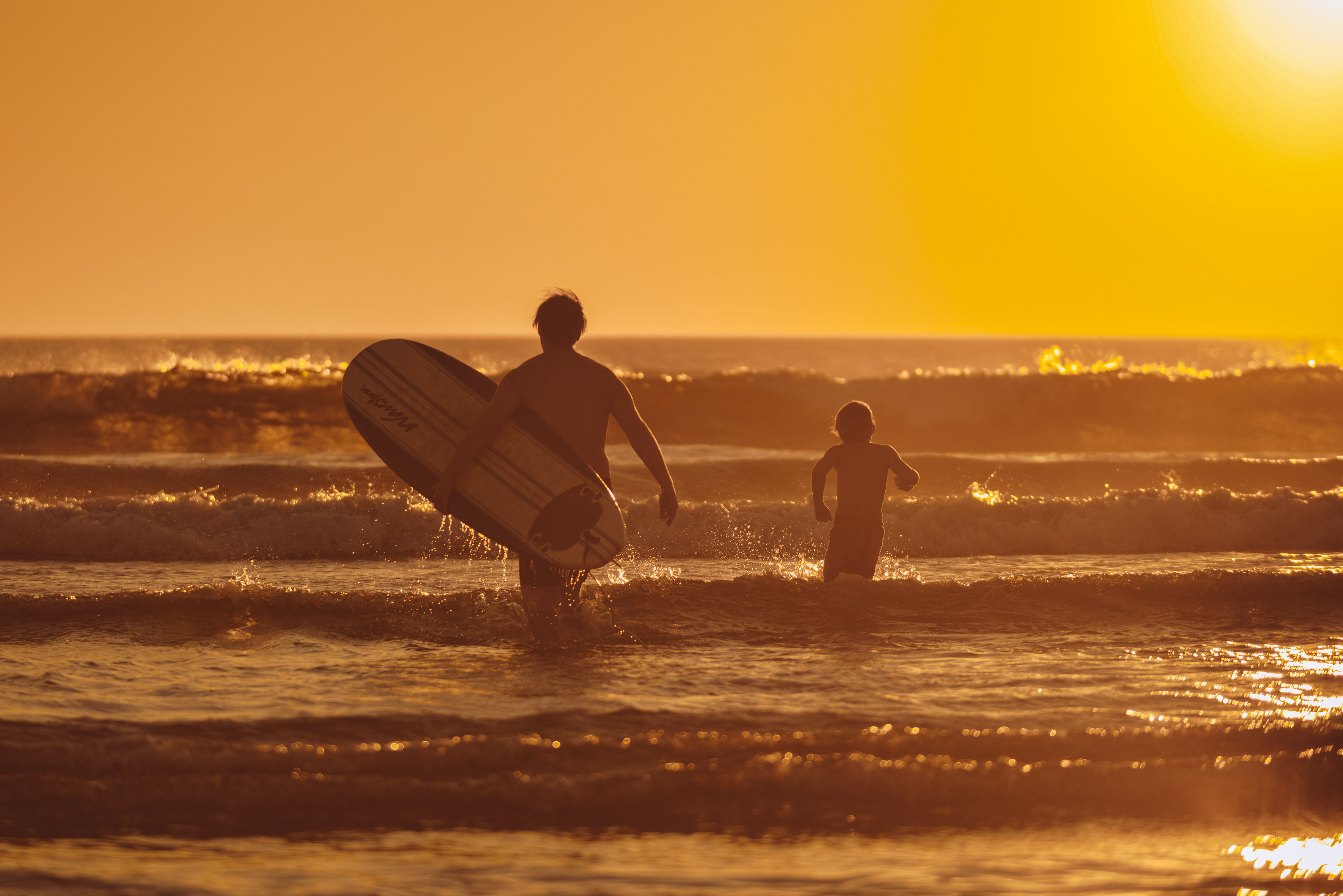 Surfer and child at sunset on Encinitas beach